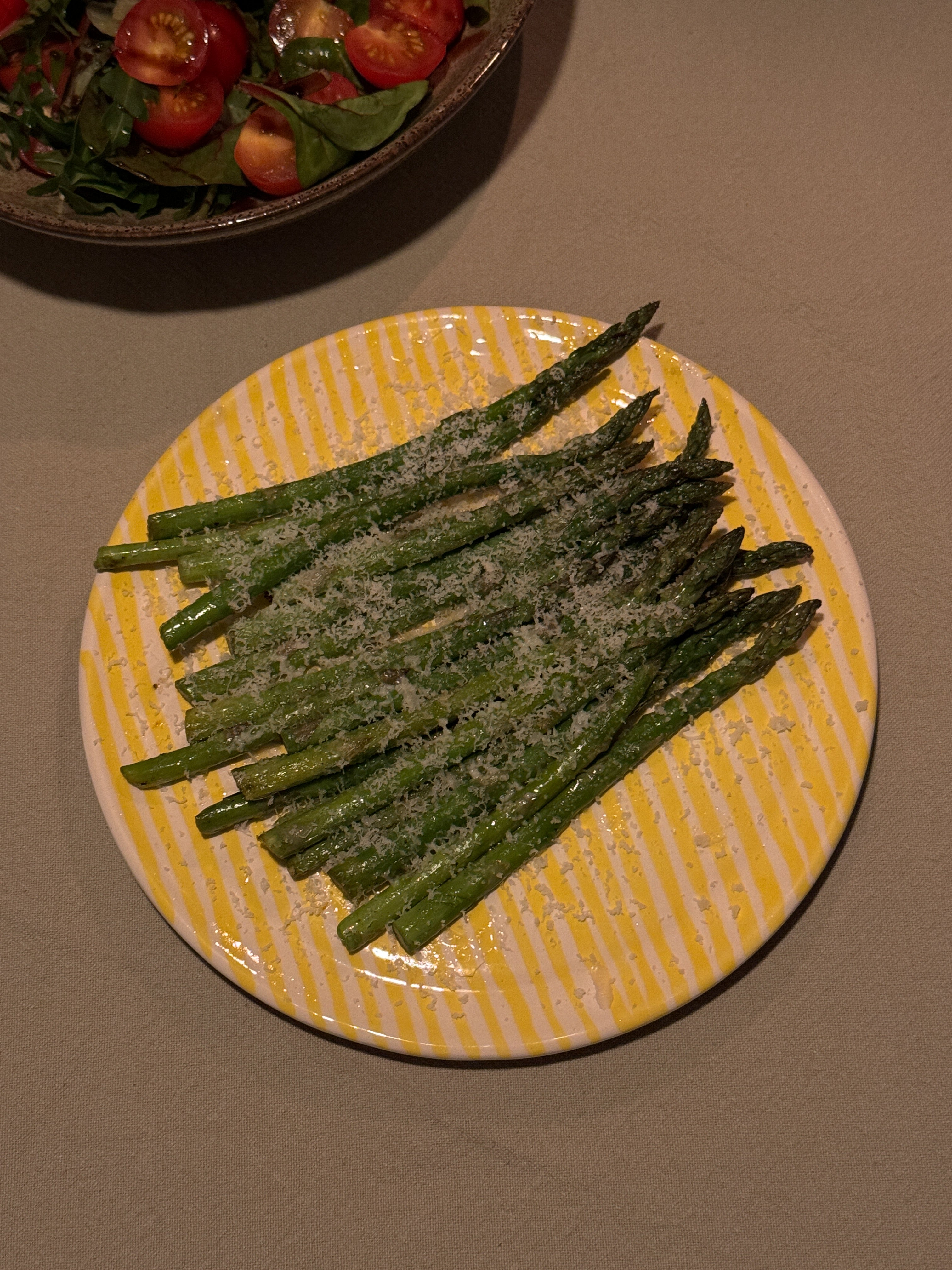 geel gestreept keramiek bordje met groene asperges erop 